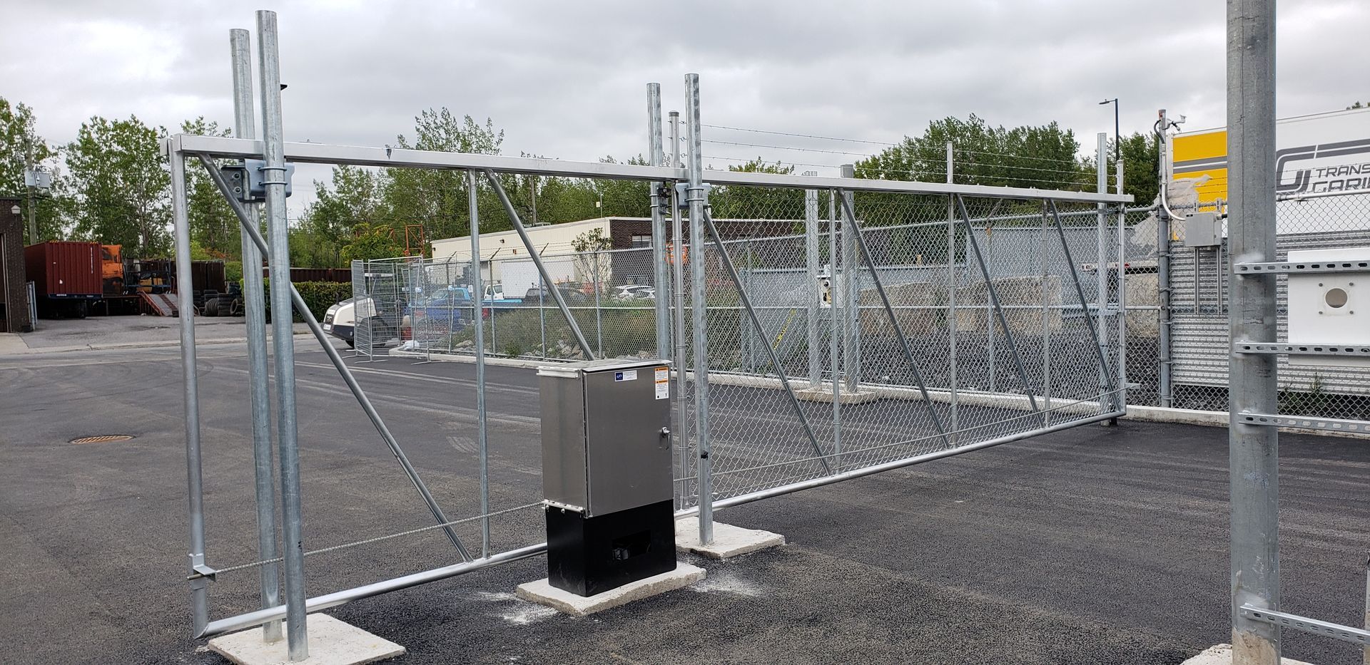 Une clôture métallique avec une boîte au milieu dans un parking.