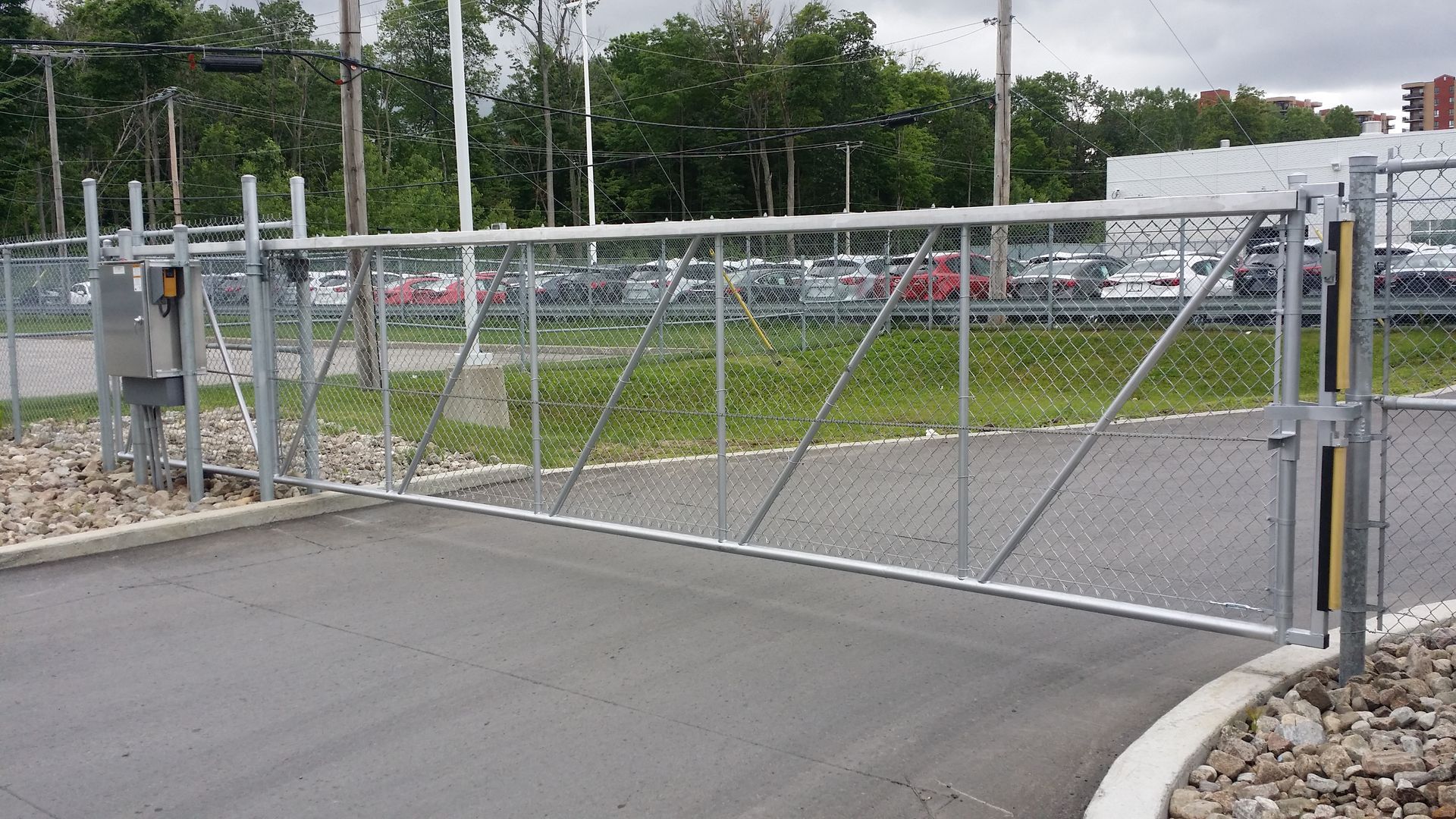 Une clôture avec un portail au milieu d'un parking.