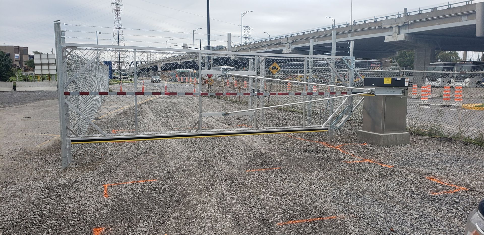 Une clôture est en cours de construction dans une zone de gravier à côté d'un pont.