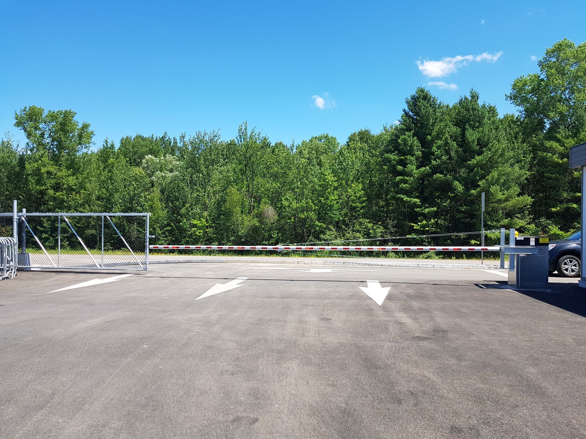 Un parking avec un portail coulissant et des arbres en arrière-plan