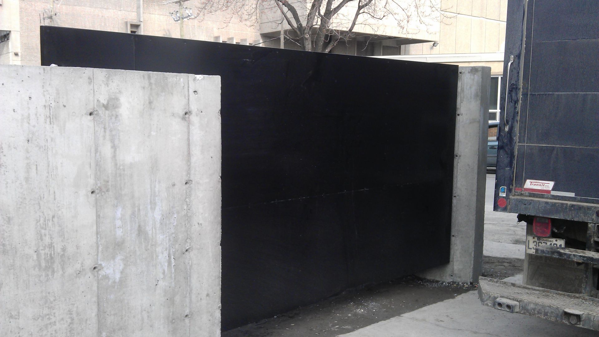 Un camion bleu est garé à côté d'un mur en béton