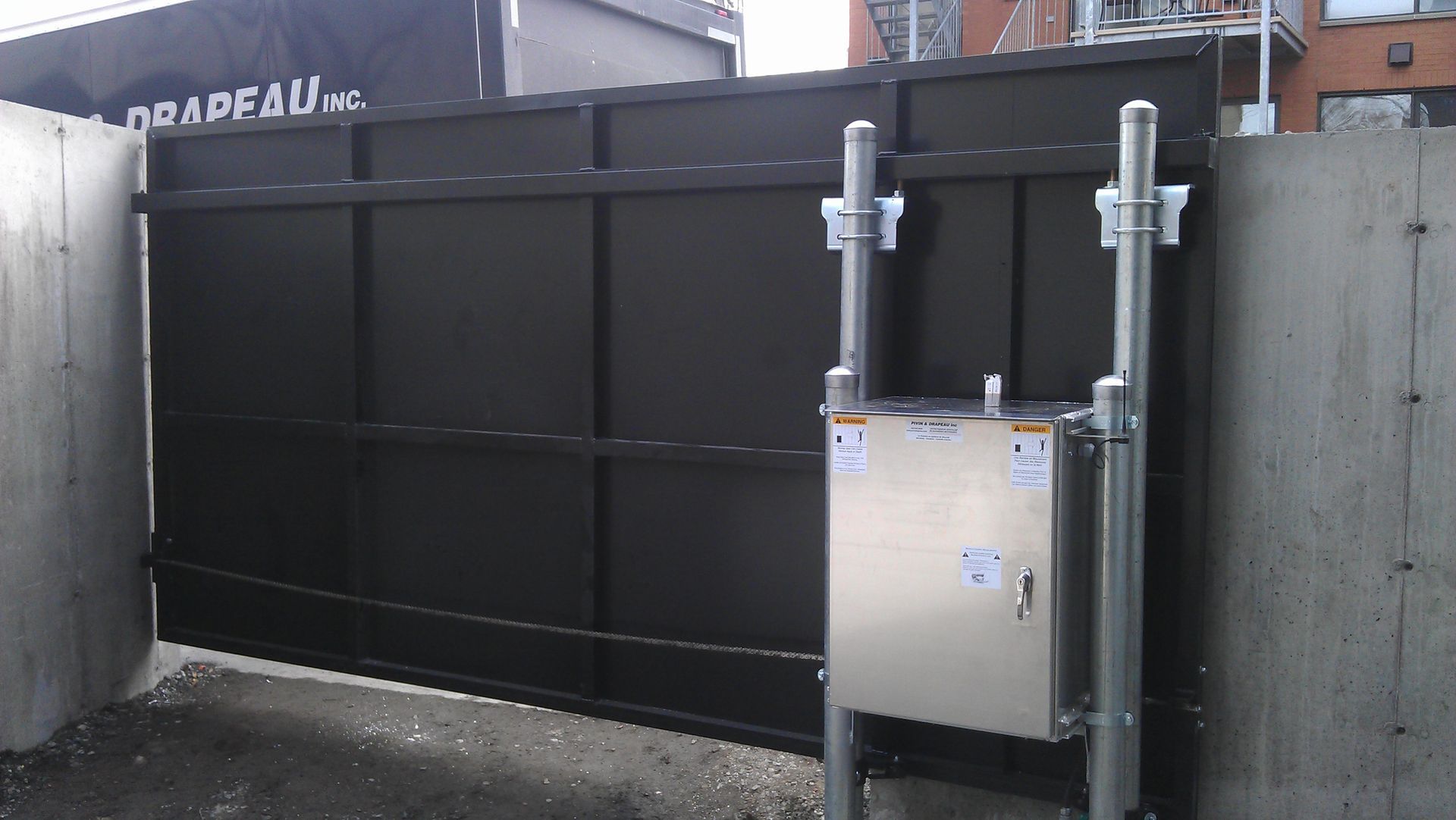 A sliding gate with a stainless steel box underneath it