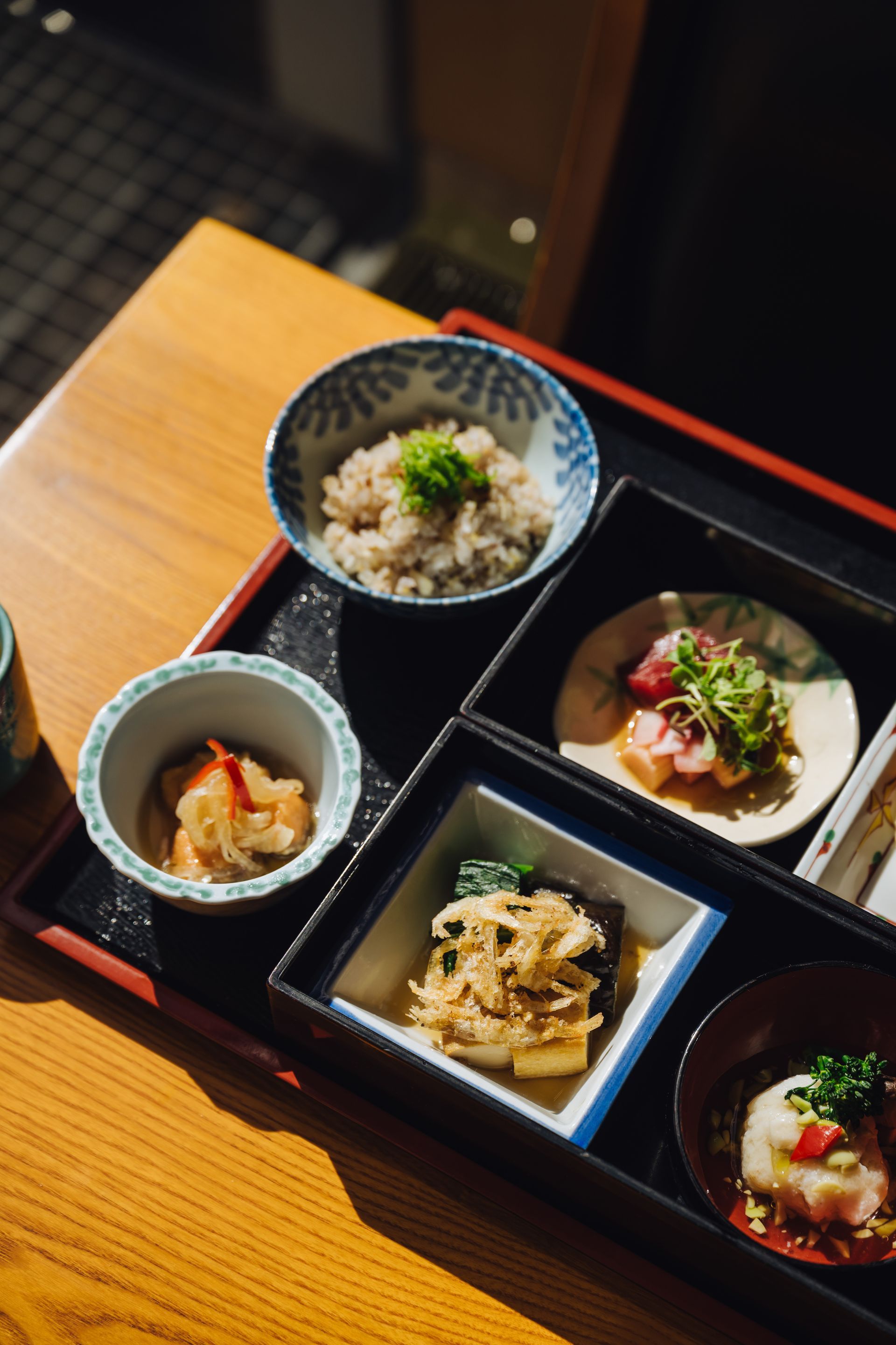Japanse bentobox met verschillende compartimenten, waaronder avocado, zeevruchten en groenten.