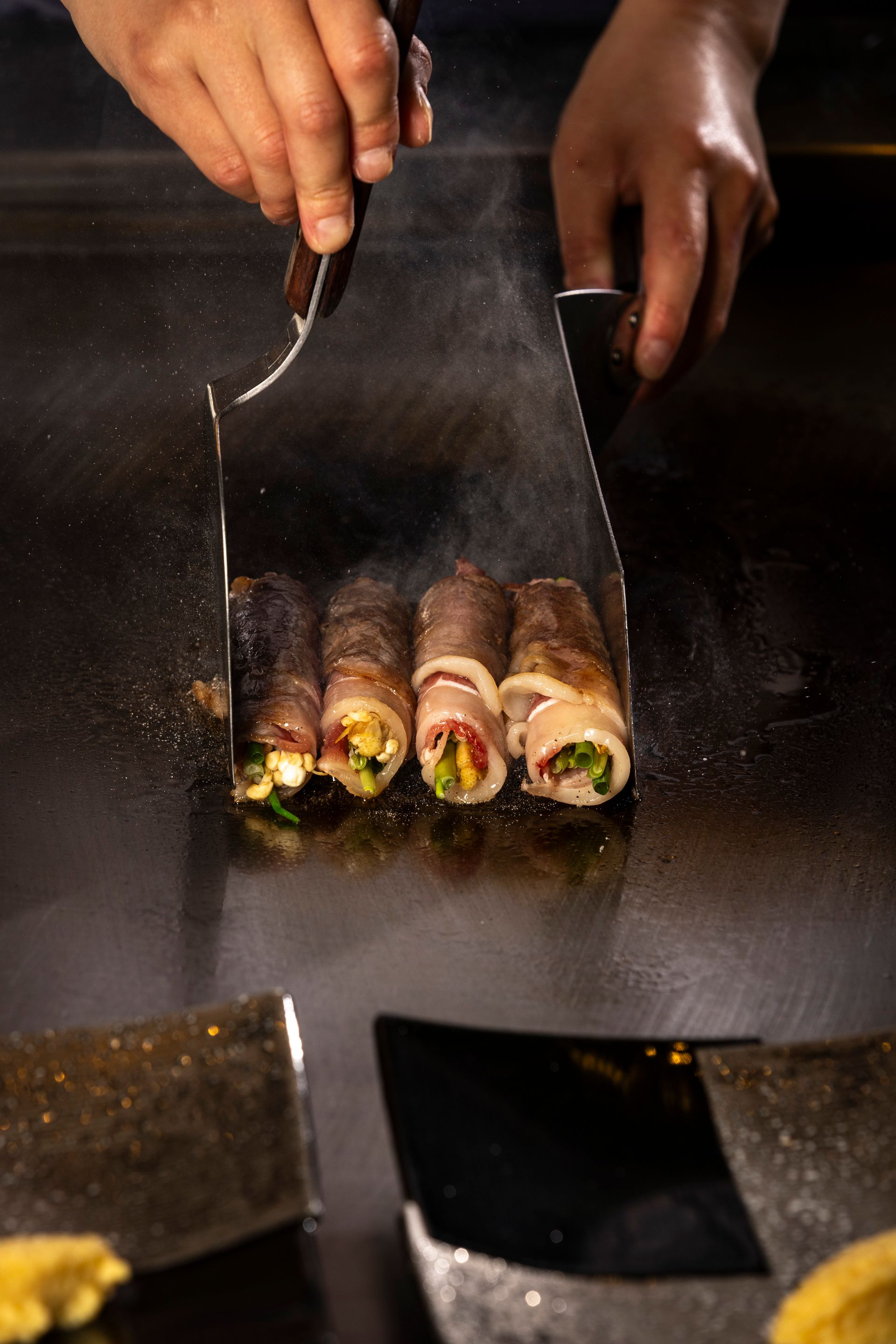 Chef presenting a plate of cooked lobster halves with a creamy topping.