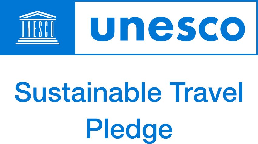 UNESCO Sustainable Travel Pledge logo in blue. Includes UNESCO logo and text: