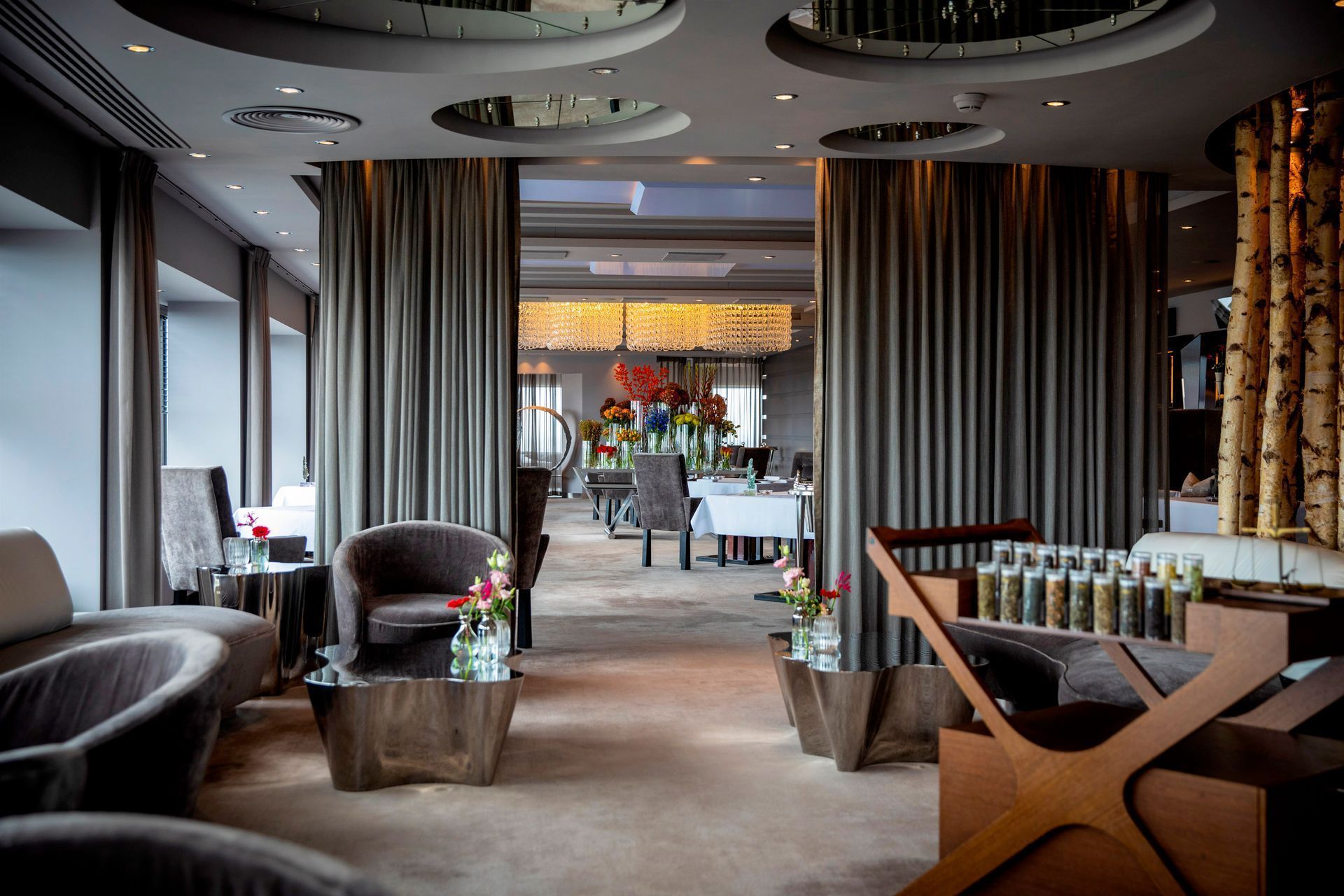 Upscale restaurant interior with plush seating, curtains, and dining tables visible through an open doorway.