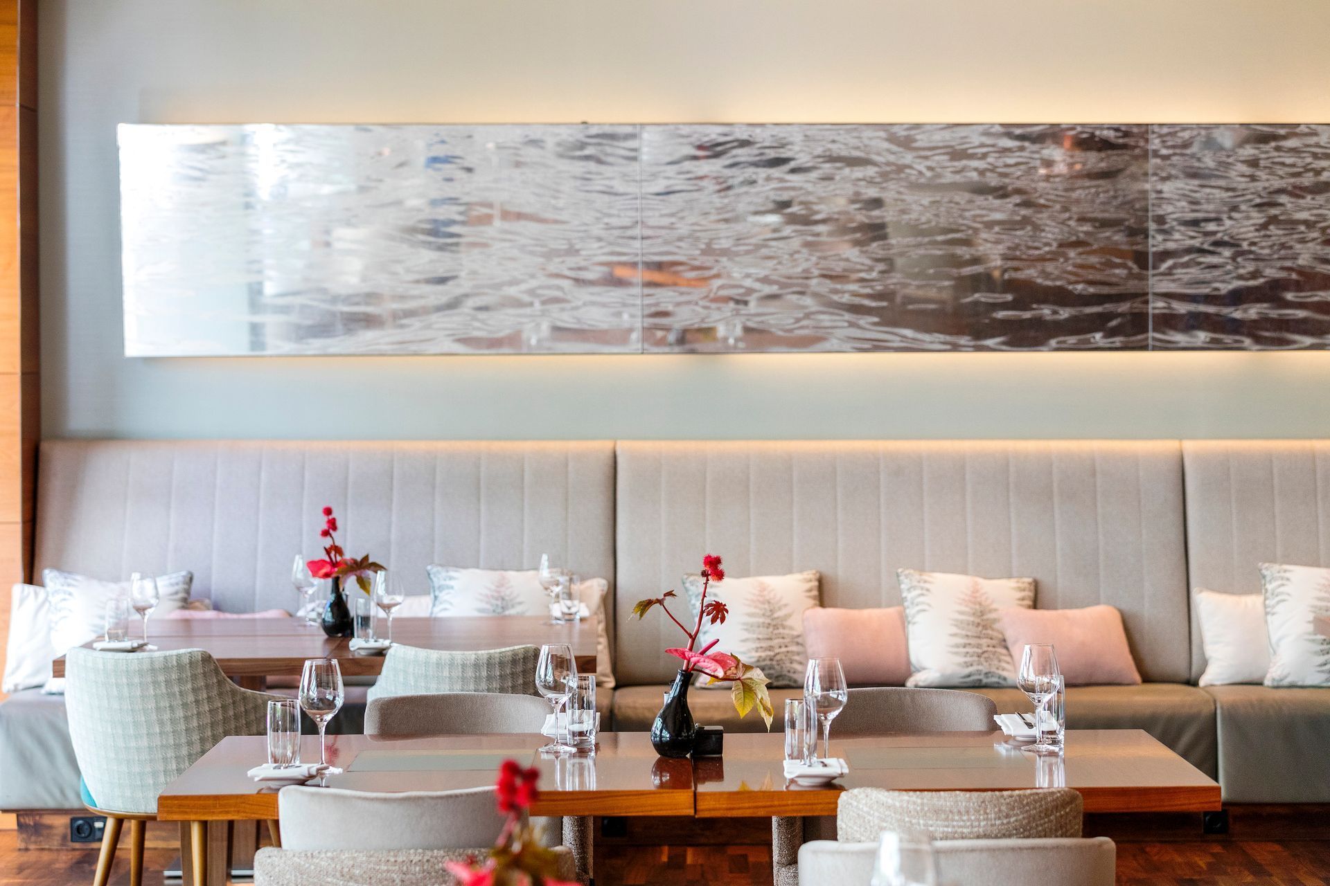 Restaurant interior with booth seating, rectangular tables, and wall art depicting water.