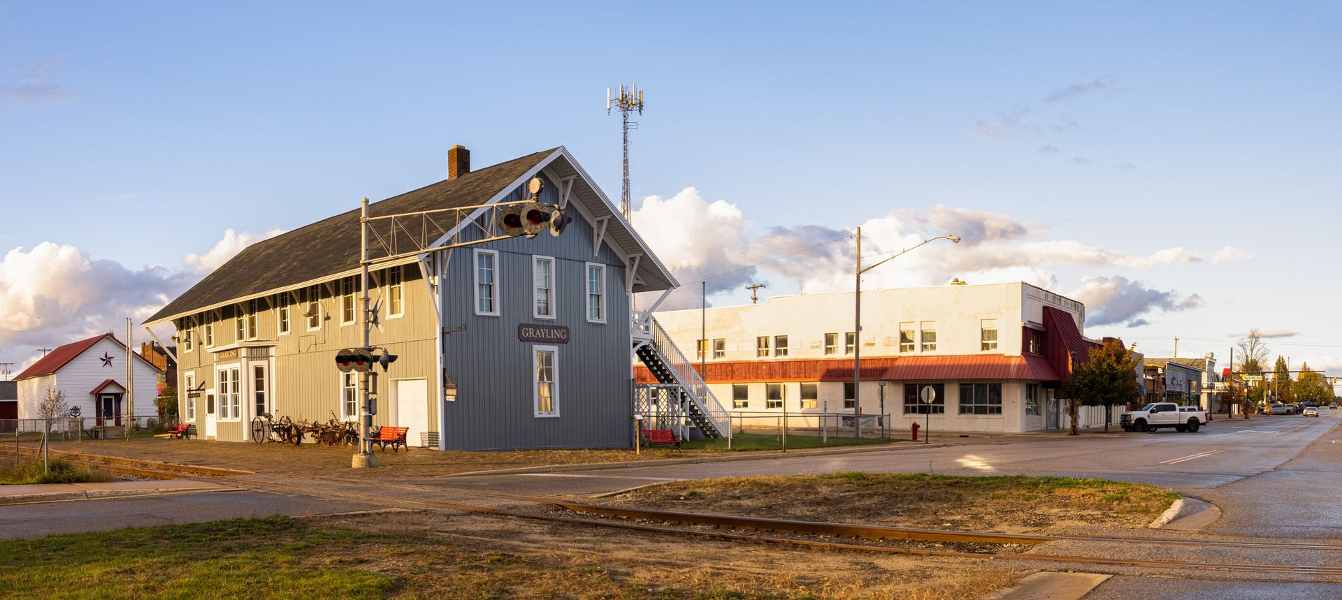 A large gray building with a red roof is in the middle of a small town.