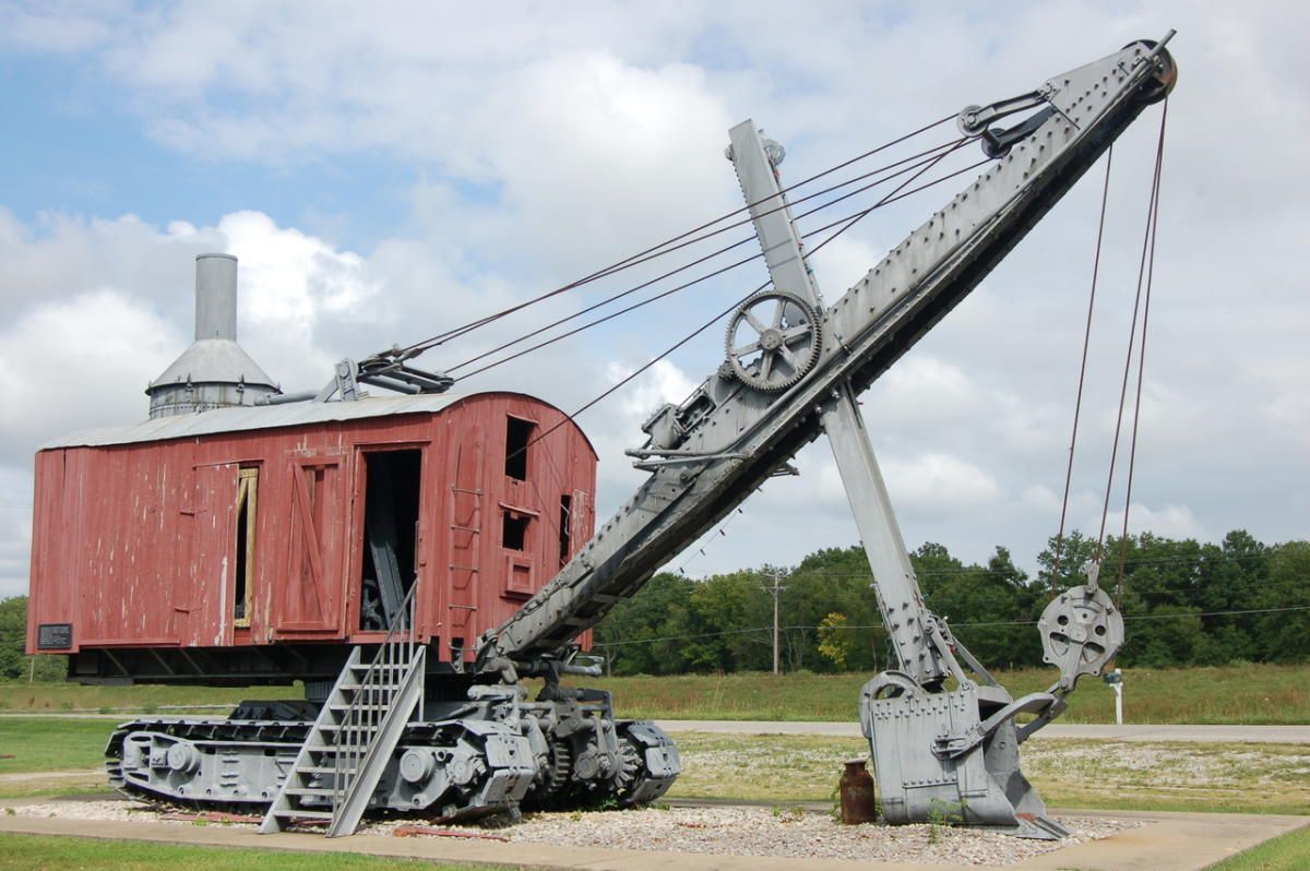 A large crane with a red building in the background
