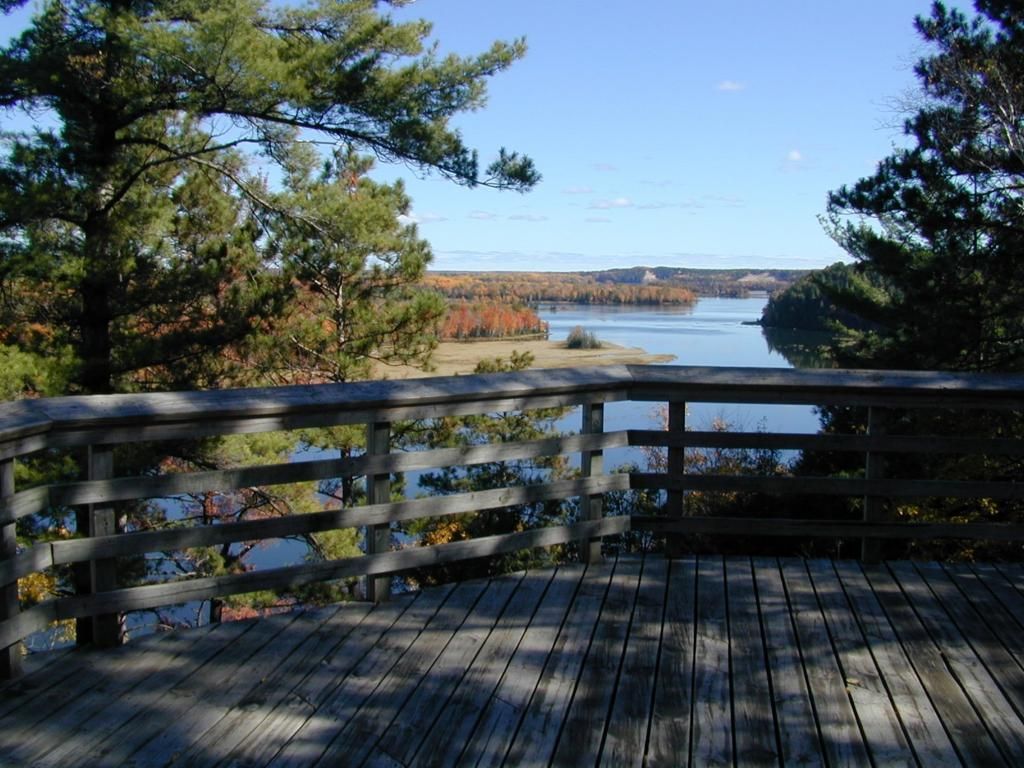 A wooden deck overlooking a lake with trees in the background