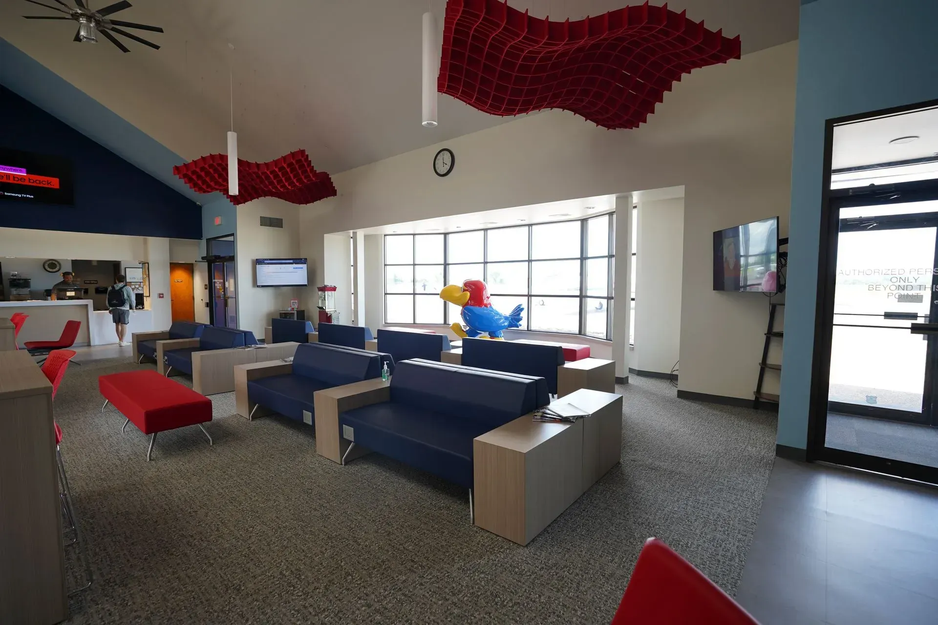 Modern lobby with blue and red sofas, bright windows, and abstract red ceiling decor