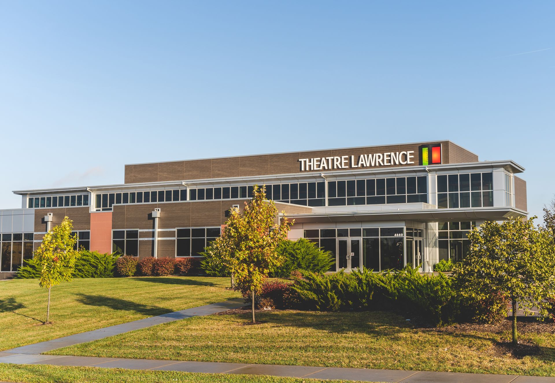 Theatre Lafayette building with a modern facade, lawn, and trees under a clear blue sky