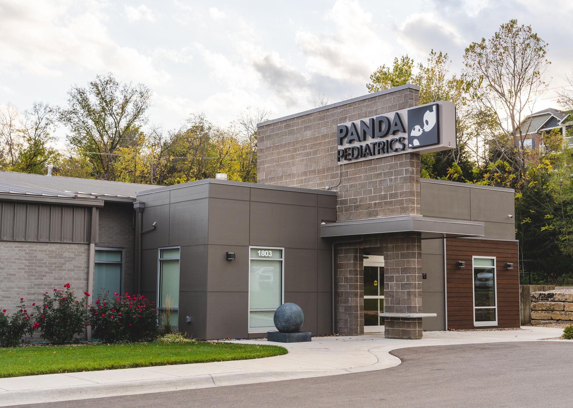 Panda Express restaurant exterior with stone facade, glass entrance, and parking lot under cloudy sky