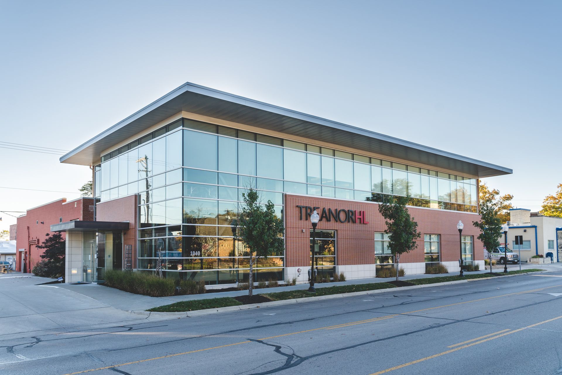 Modern brick-and-glass office building on a quiet street at sunset