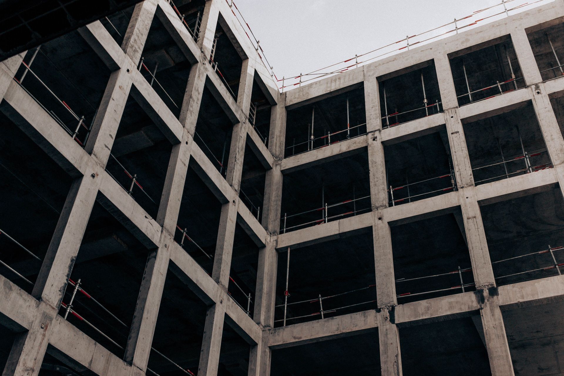 Low-angle view of a concrete building courtyard with dark windows and geometric balconies