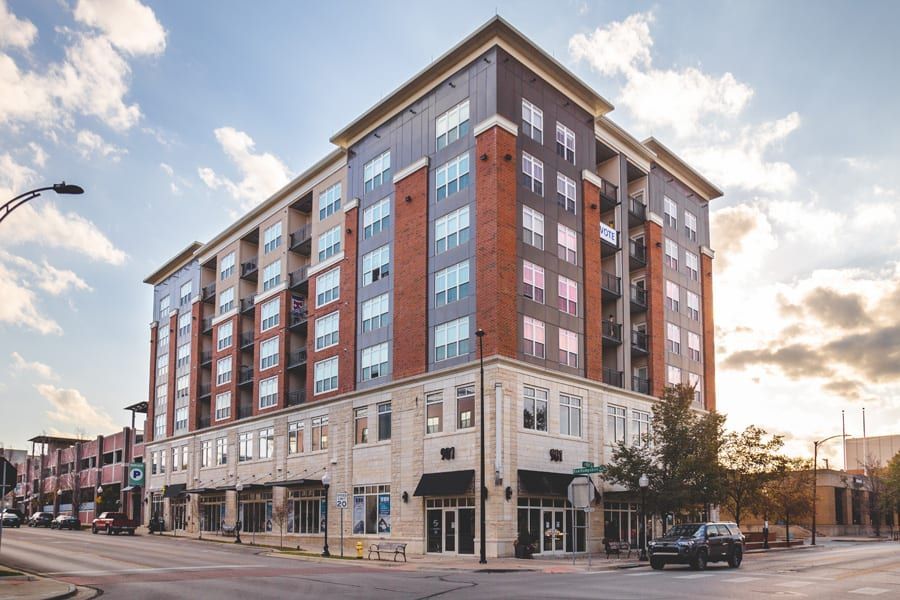 Modern multi-story brick and stone apartment building on a city street at sunset