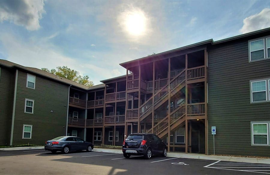 Apartment building exterior with parked cars and exterior stairways in daylight