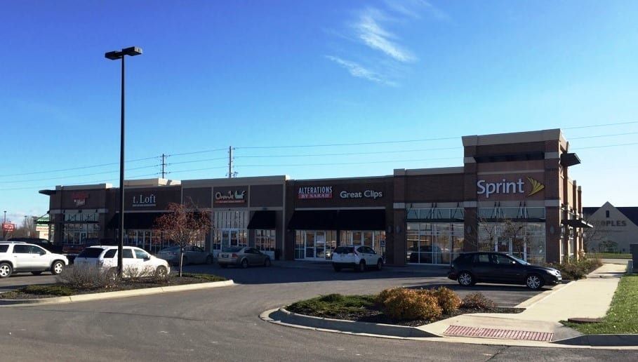 Strip mall with a Sprint store and parked cars on a sunny day