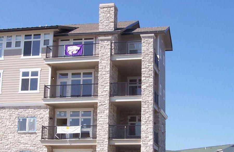 Apartment building with balconies and stone facade under a clear blue sky