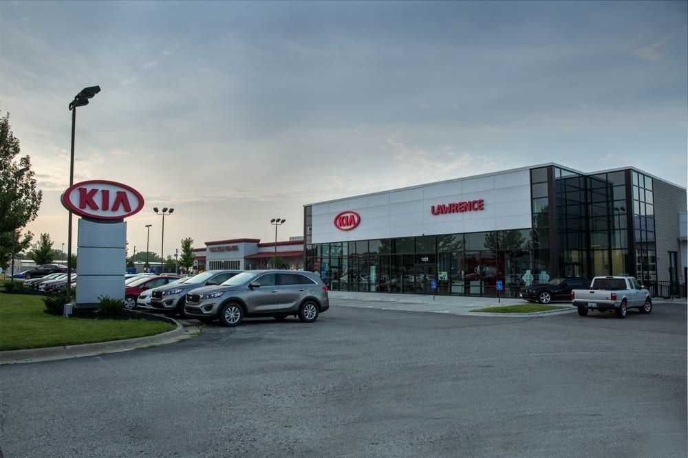 Kia dealership exterior with parked cars and a showroom at dusk