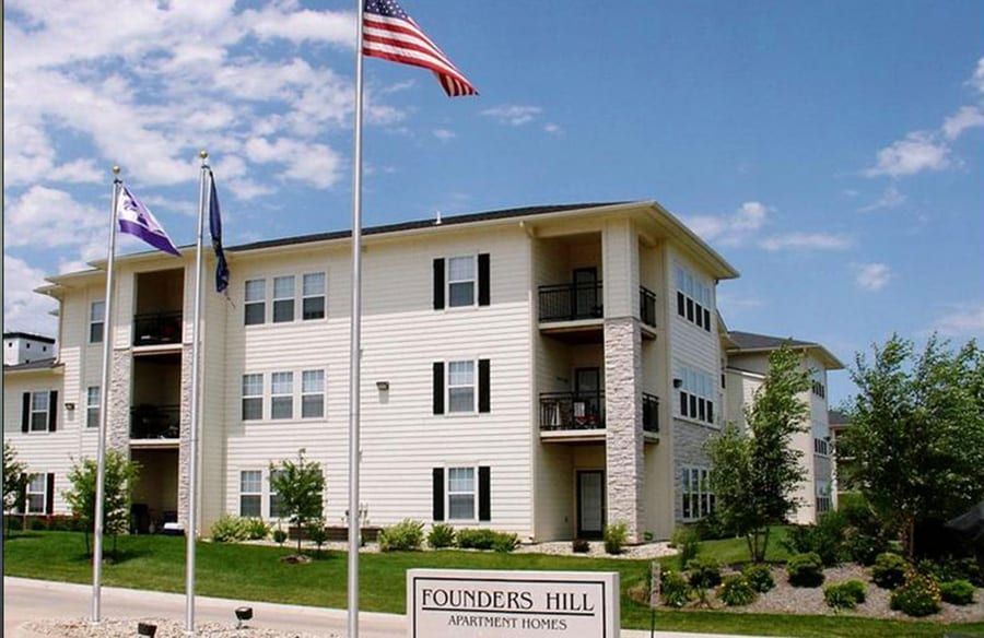 Founders Hall apartment building with flags and sign under a blue sky