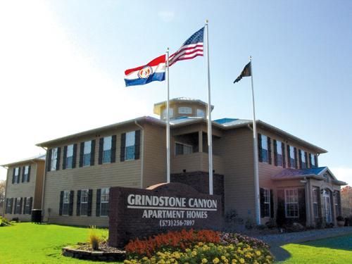 Grindstone Canyon Apartment Homes building with three flags waving on a sunny day