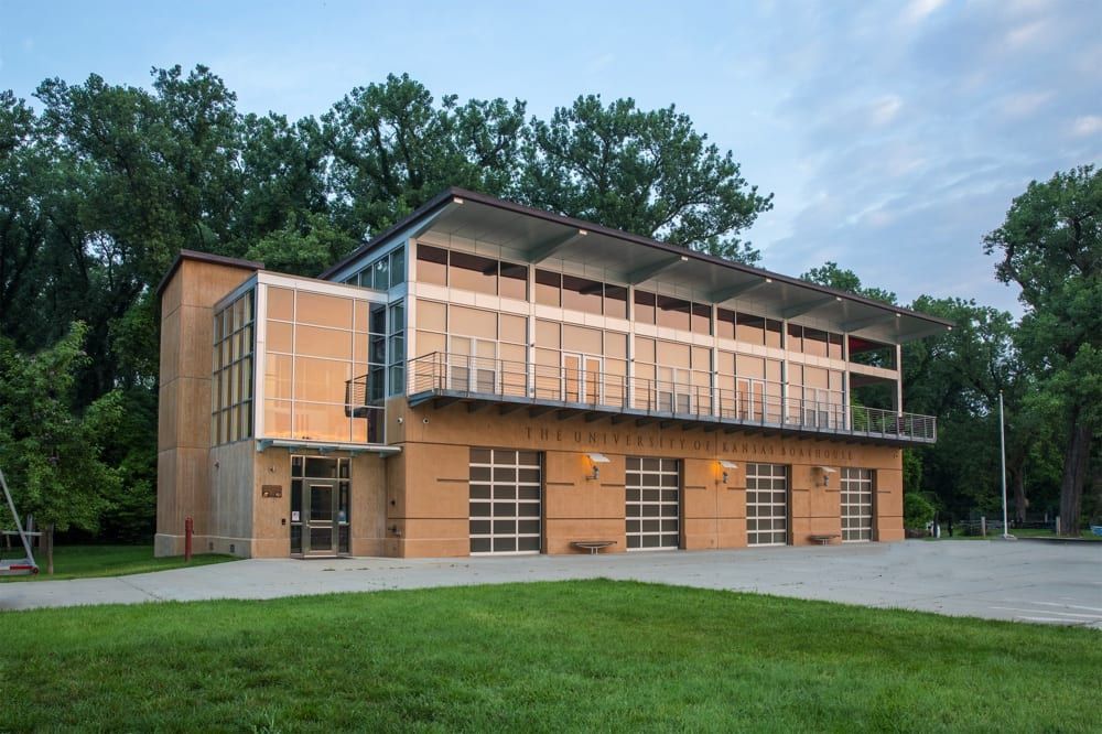 Modern two-story building with wood and glass exterior beside a grassy lawn and trees