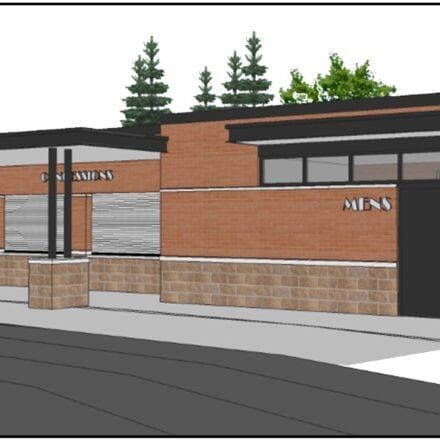 Brick storefront exterior with “WOMEN’S” and “MEN’S” signs and closed metal shutters.