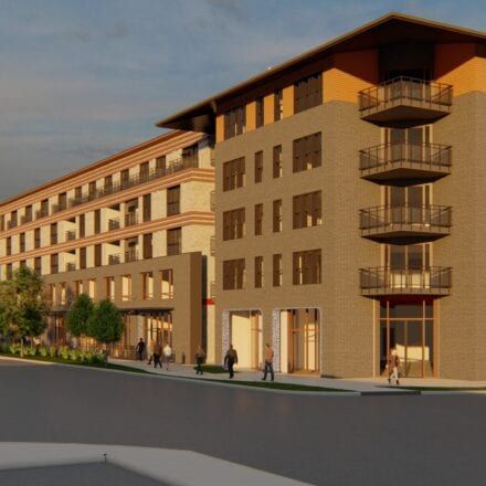 Modern multi-story apartment building with balconies and pedestrians on the sidewalk at sunset