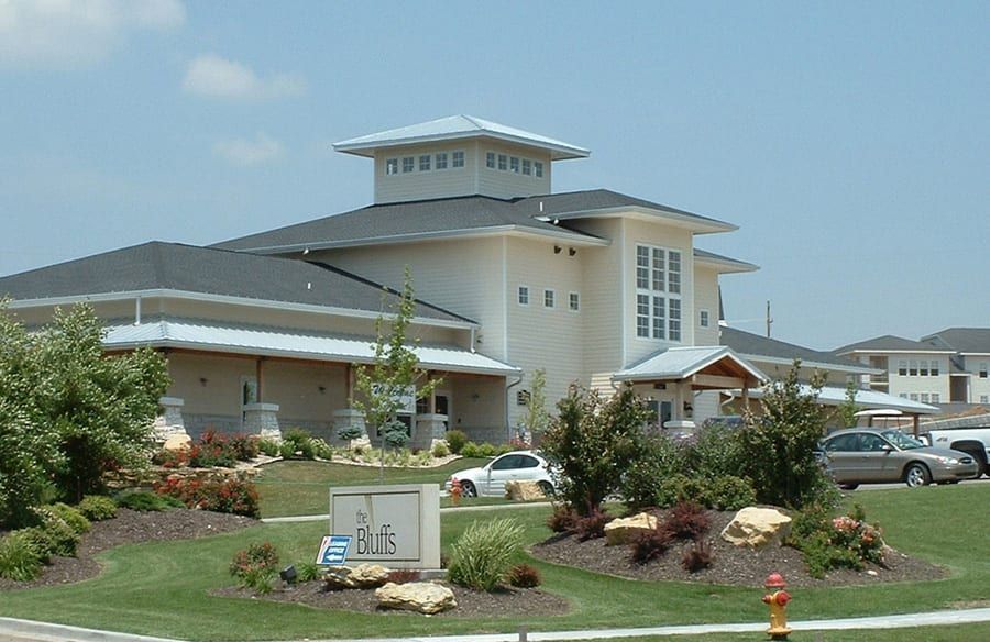 Modern church building with white walls, gray roof, and landscaped entrance under a clear sky