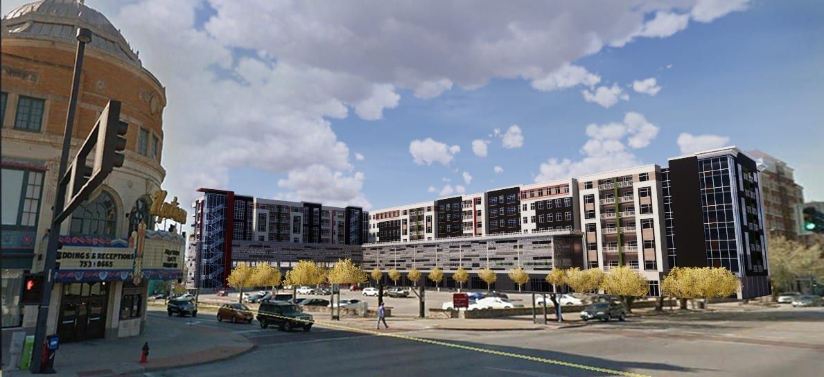 Street view of modern apartment buildings beside a curved brick corner building under a cloudy sky