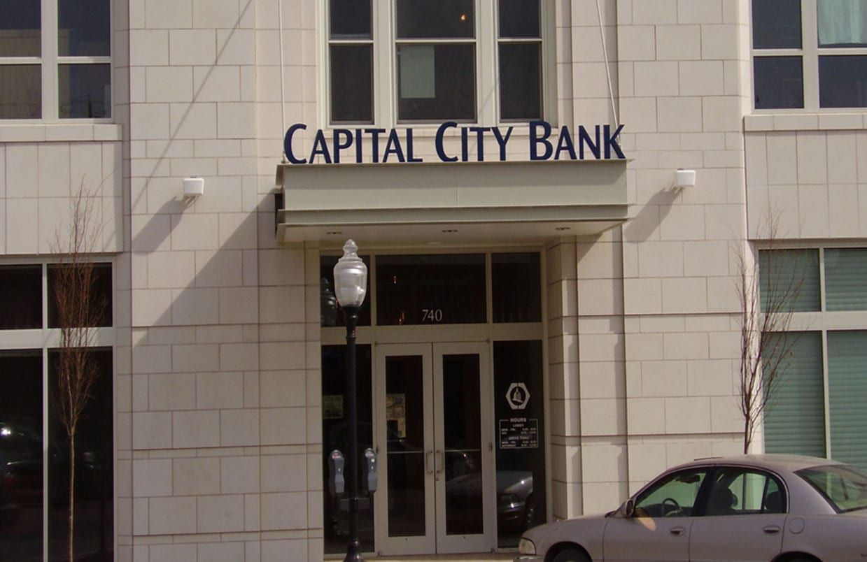 Capital City Bank storefront with glass entrance and parked car in front