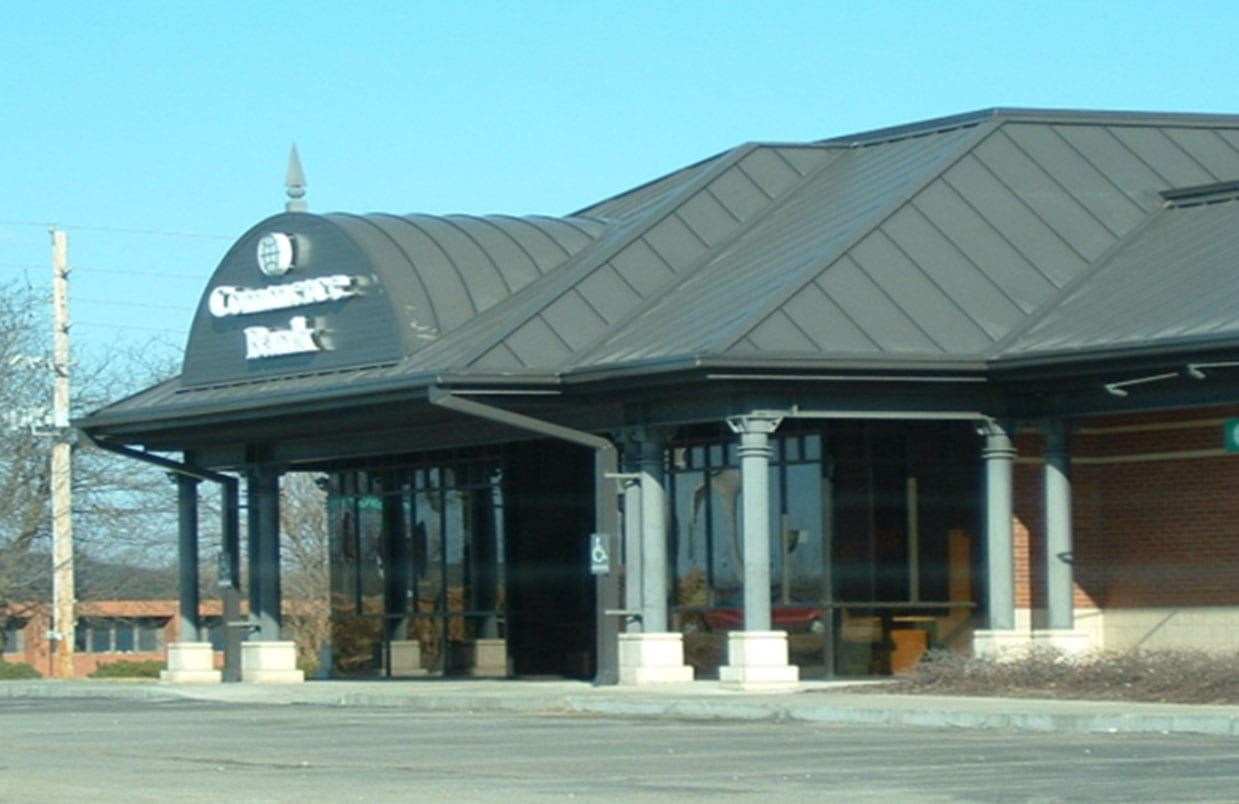 Tire store with a dark metal roof and glass entrance on a sunny day