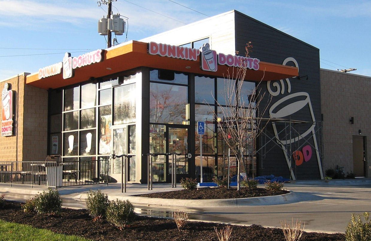 Dunkin’ Donuts storefront with glass windows and orange signage on a sunny street corner