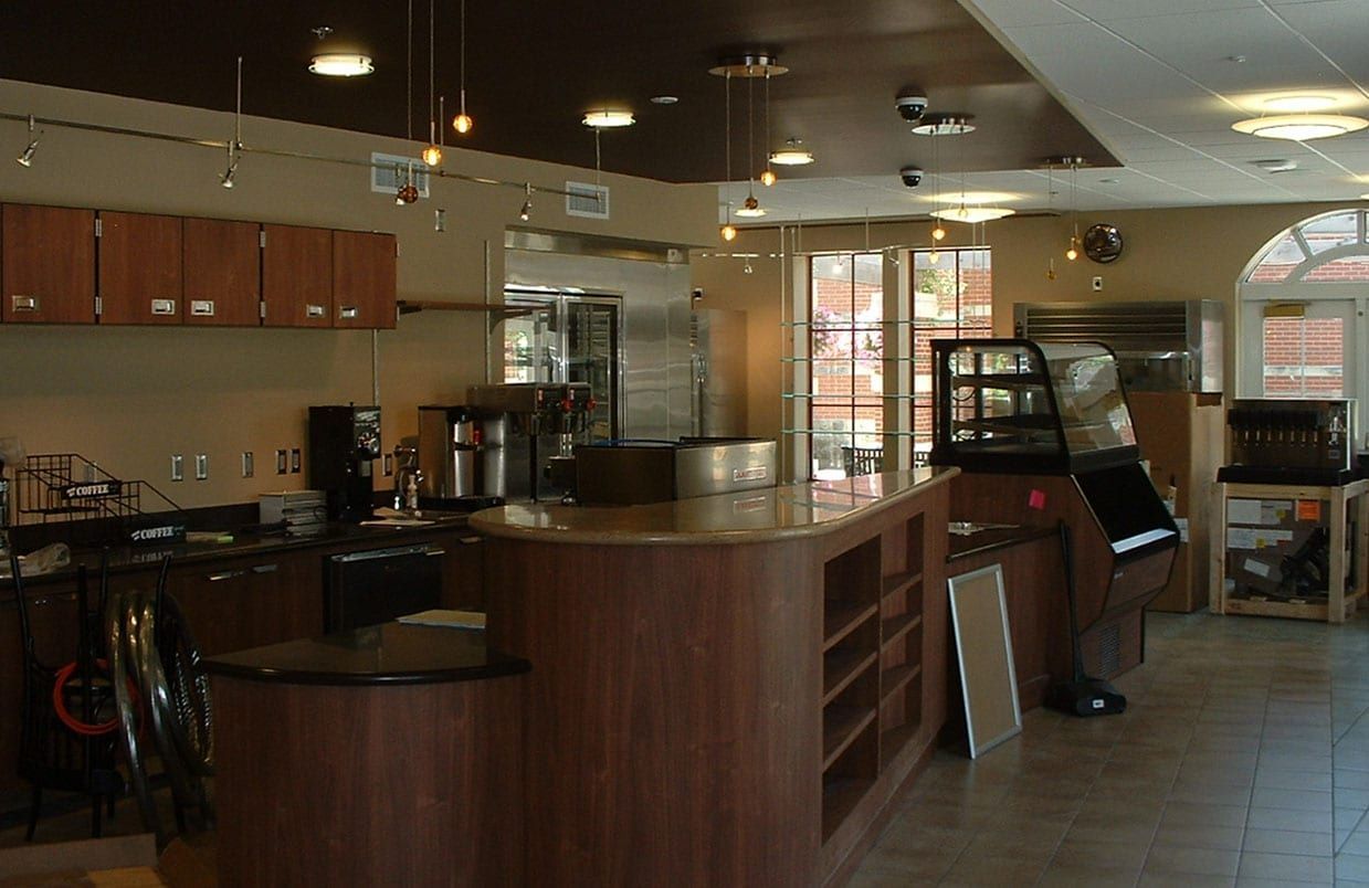 Empty café interior with wooden counter, tables, chairs, and warm lighting