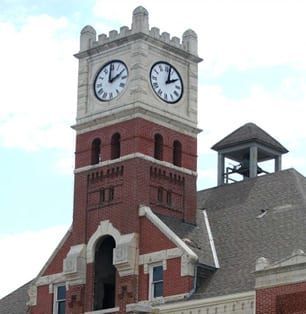 Red brick clock tower with four white clock faces on a historic building