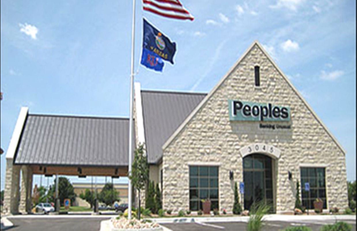 People's bank building with stone facade, American and state flags, and drive-thru canopy