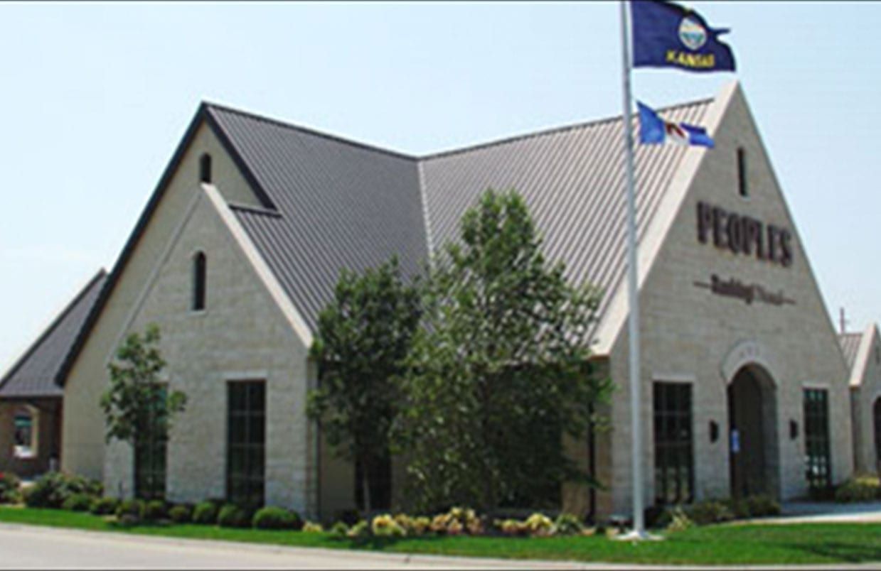 Stone church building with a steep gray roof and sign reading “Veritas” near the entrance.