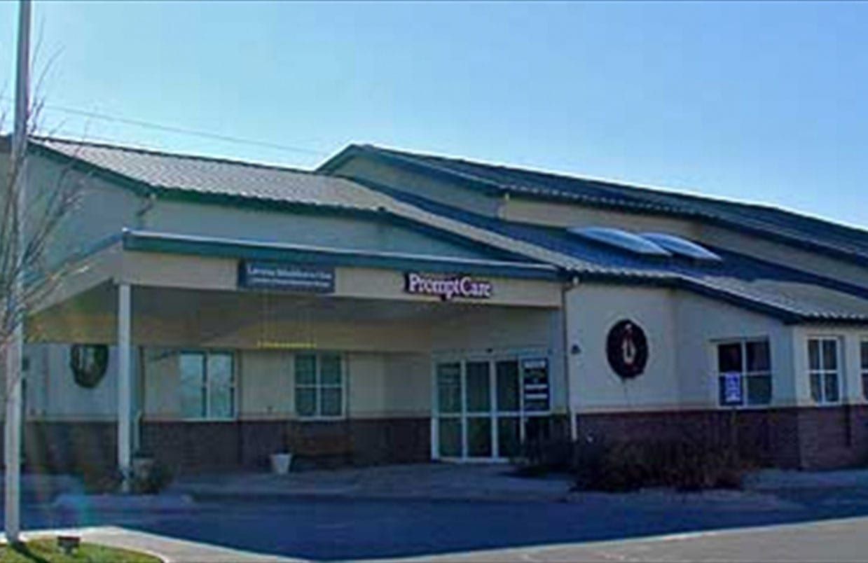 Exterior of a suburban clinic building with a covered entrance and large windows under a blue sky
