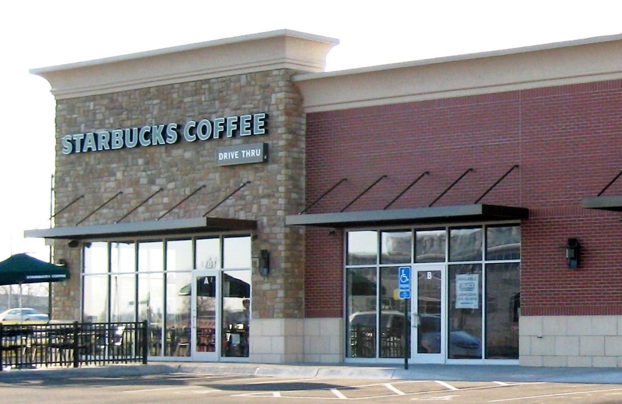Starbucks Coffee storefront with stone facade, glass doors, and outdoor patio seating