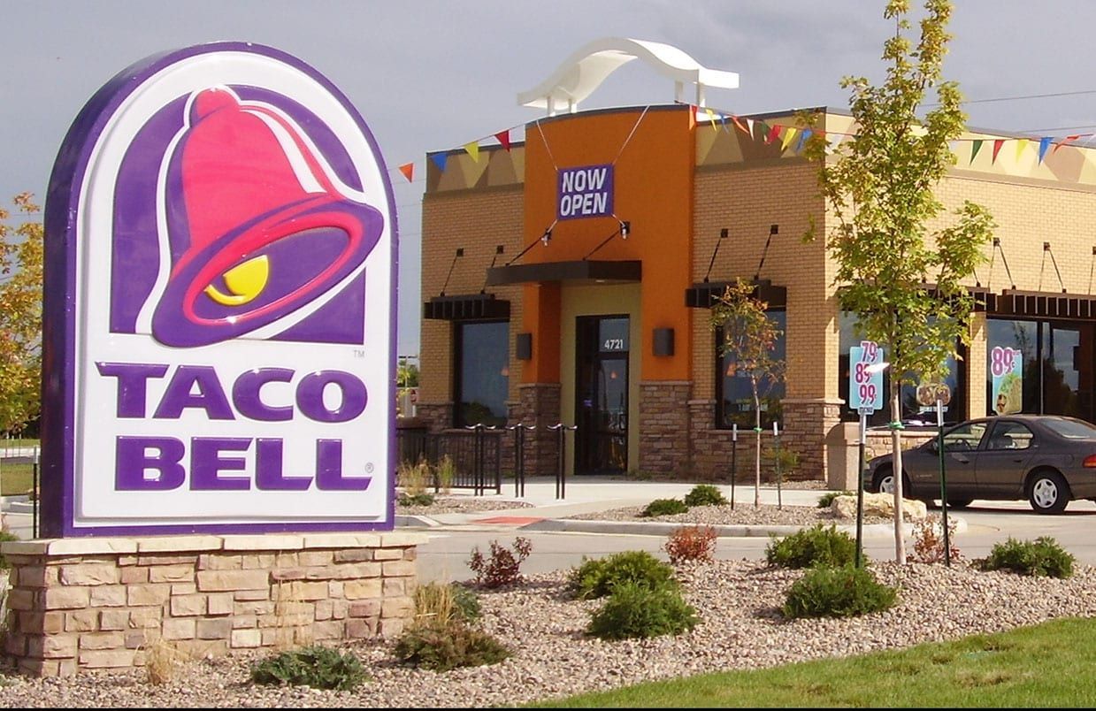 Taco Bell restaurant exterior with large purple sign and desert landscaping