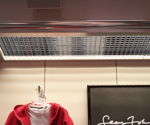 A red hoodie is hanging on a rack next to a sign that says sean john