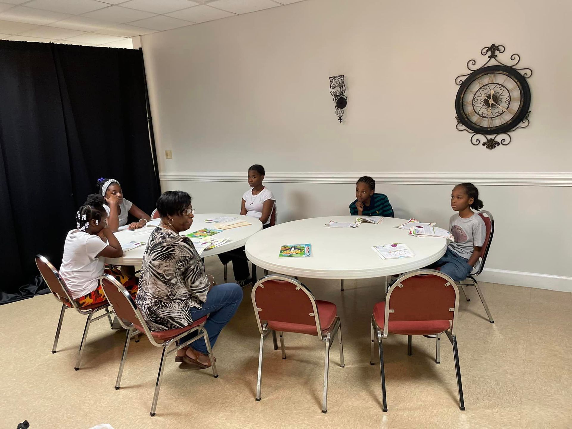Group of people sitting at tables in a room, engaged in an activity.