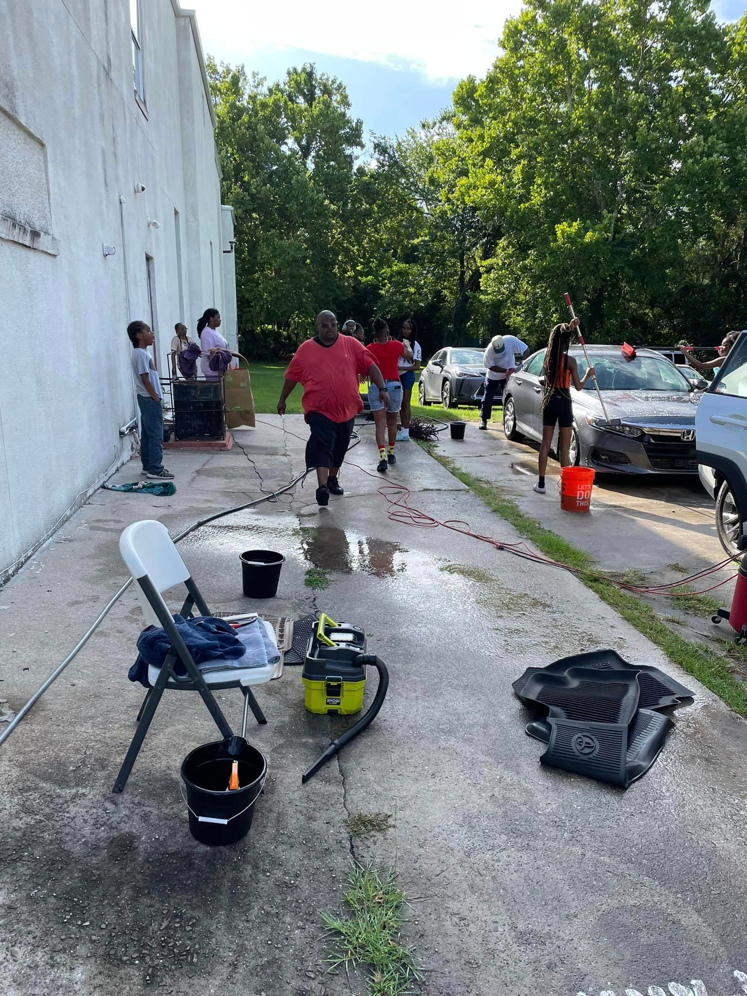 People washing cars in an outdoor setting. Some are running while others are washing the cars.