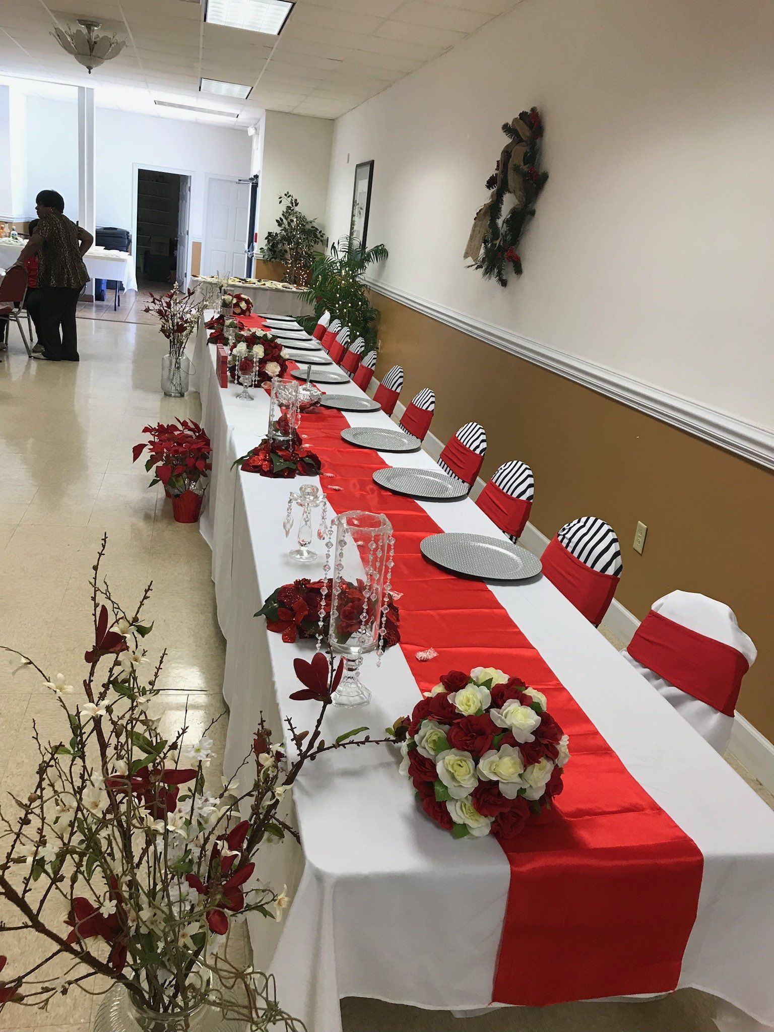 Long table set for a formal event, red and white décor, with chairs and floral arrangements.