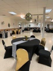 Round table with black tablecloth and silver runner, surrounded by chairs. Disco ball hangs overhead in a ballroom.