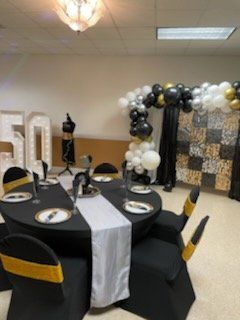 Party room decorated for a 50th birthday, with balloons, tables, and a number 