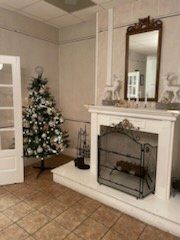 Christmas tree next to fireplace with a mirror, deer figurines, and a decorative screen.