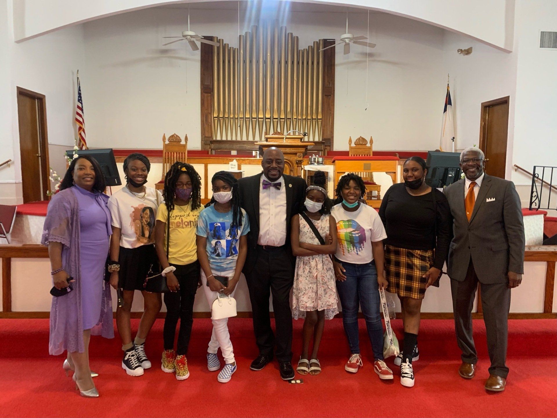 Group of people pose inside a church with a red carpet. The group consists of men and children.