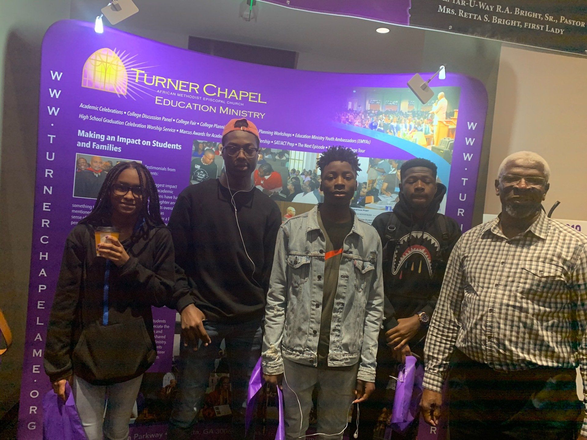 Group of people standing in front of a purple banner for Turner Chapel Ed.